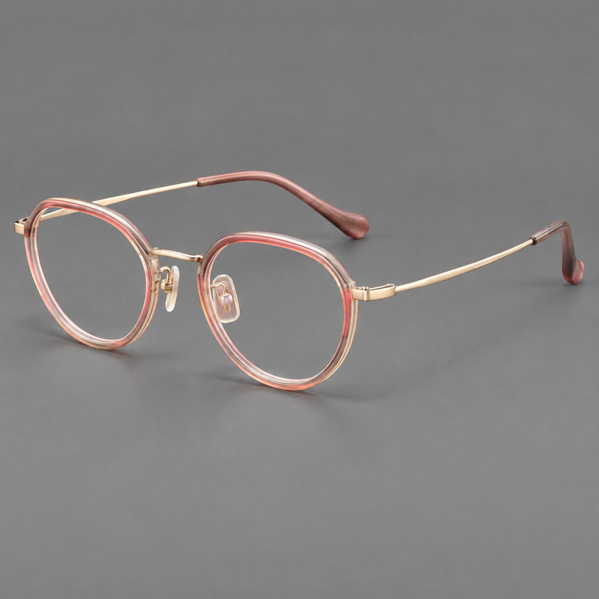 Rounded eyeglasses in acetate and titanium with gently arched brows and engraved metal temples in Amber Pink / Gold, three quarter view