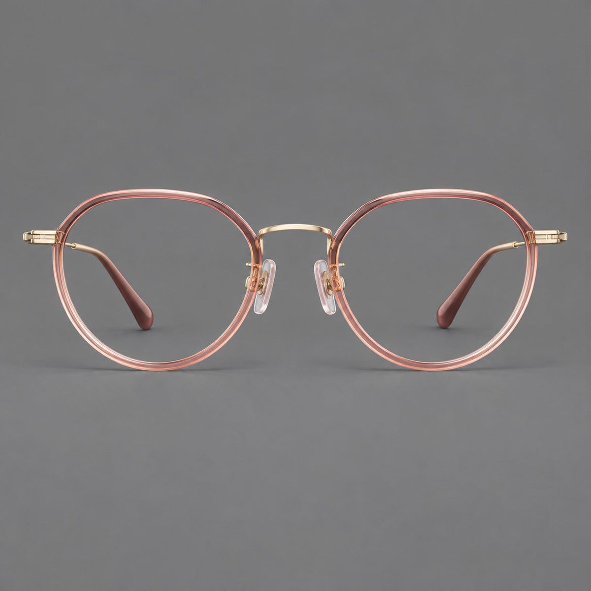 Rounded eyeglasses in acetate and titanium with gently arched brows and engraved metal temples in Amber Pink / Gold, front view