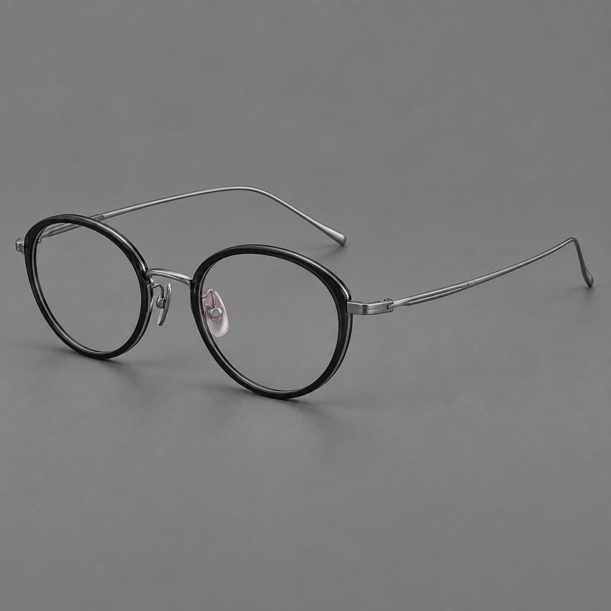 Round eyeglasses in acetate and titanium with a slim curved bridge and fine metal temples in Glossy Black / Gunmetal, three quarter view