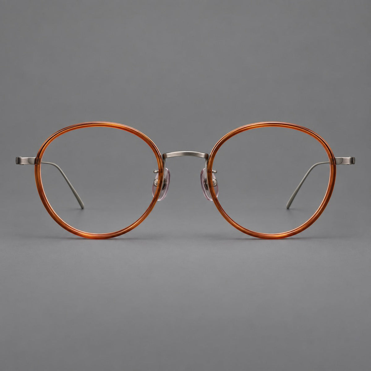 Classic round eyeglasses in acetate and titanium with slim rims and textured metal temples in Tea Brown / Gunmetal, front view