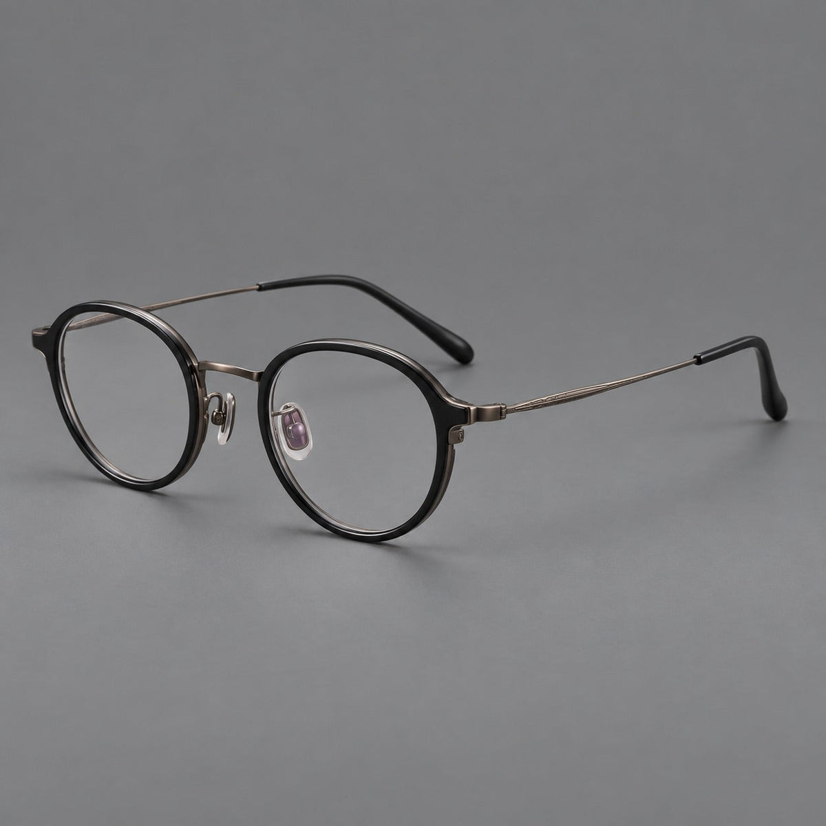 Softly rounded eyeglasses in acetate and titanium with a curved bridge and engraved temples in Matte Black / Antique Copper, three quarter view