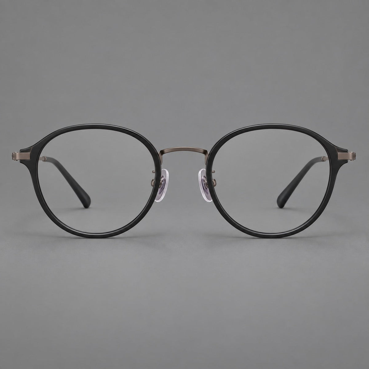 Softly rounded eyeglasses in acetate and titanium with a curved bridge and engraved temples in Matte Black / Antique Copper, front view