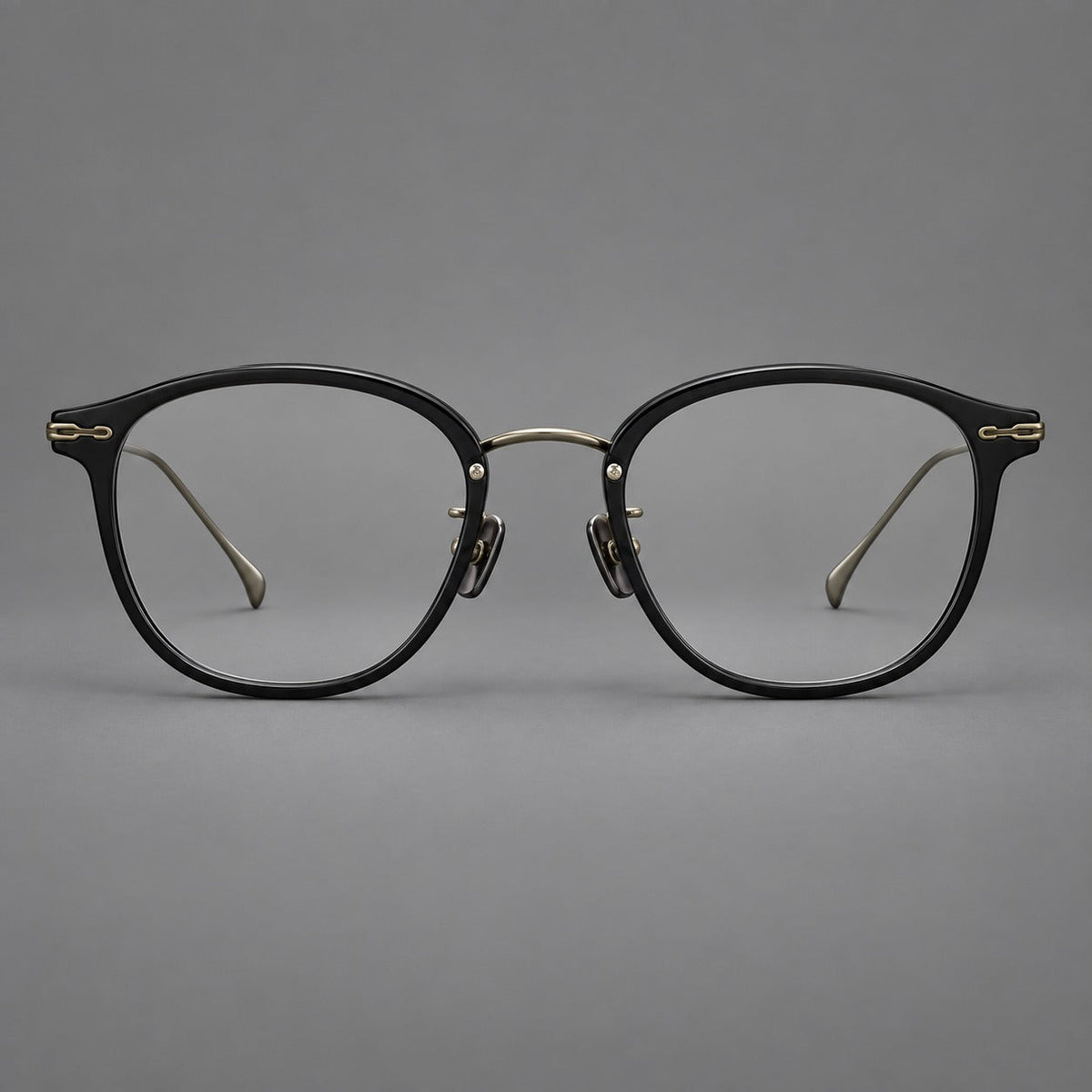 Panto eyeglasses in acetate and titanium with curved brows and decorative metal corner accents in Glossy Black / Antique Bronze, front view
