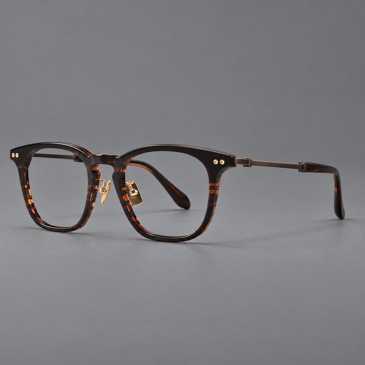 Retro acetate and titanium eyeglasses with gently squared rims and circular metal hinges in Striped Dark Brown / Antique Bronze, three quarter view
