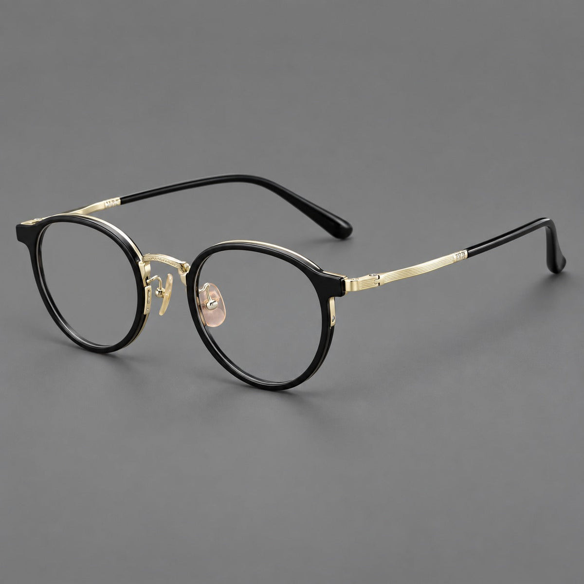 Round eyeglasses in acetate and titanium with widened outer corners and slender metal temples in Glossy Black / Gold, three quarter view