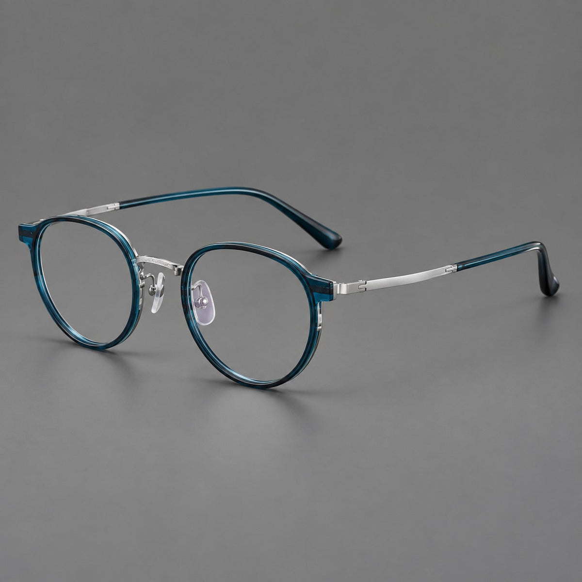 Round eyeglasses in acetate and titanium with widened outer corners and slender metal temples in Peacock Blue / Silver, three quarter view
