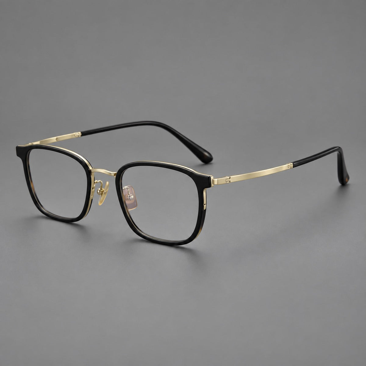 Rounded rectangular eyeglasses in acetate and titanium with bold corners and engraved metal temples in Glossy Black / Gold, three quarter view