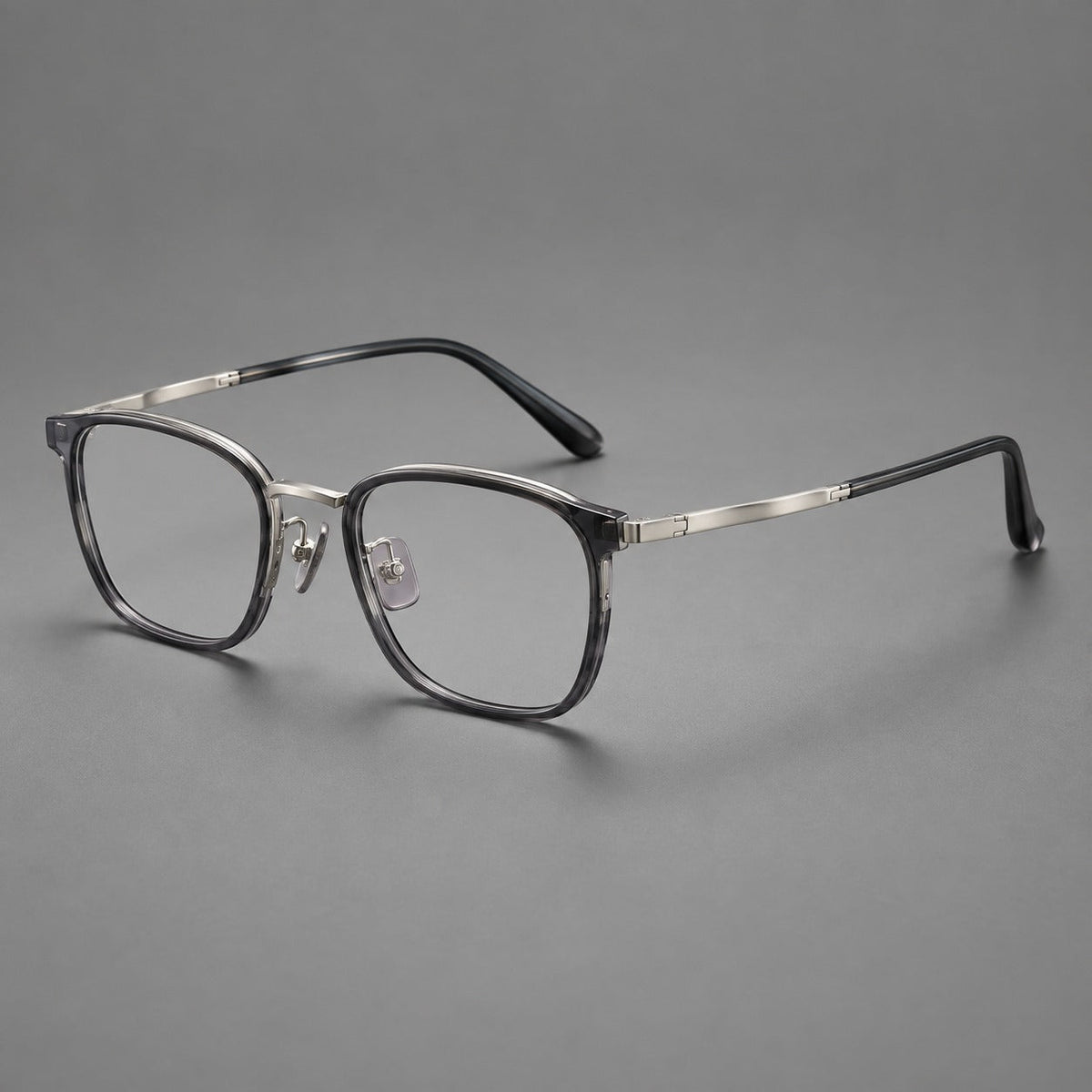 Rounded rectangular eyeglasses in acetate and titanium with bold corners and engraved metal temples in Clear Gray / Gunmetal, three quarter view
