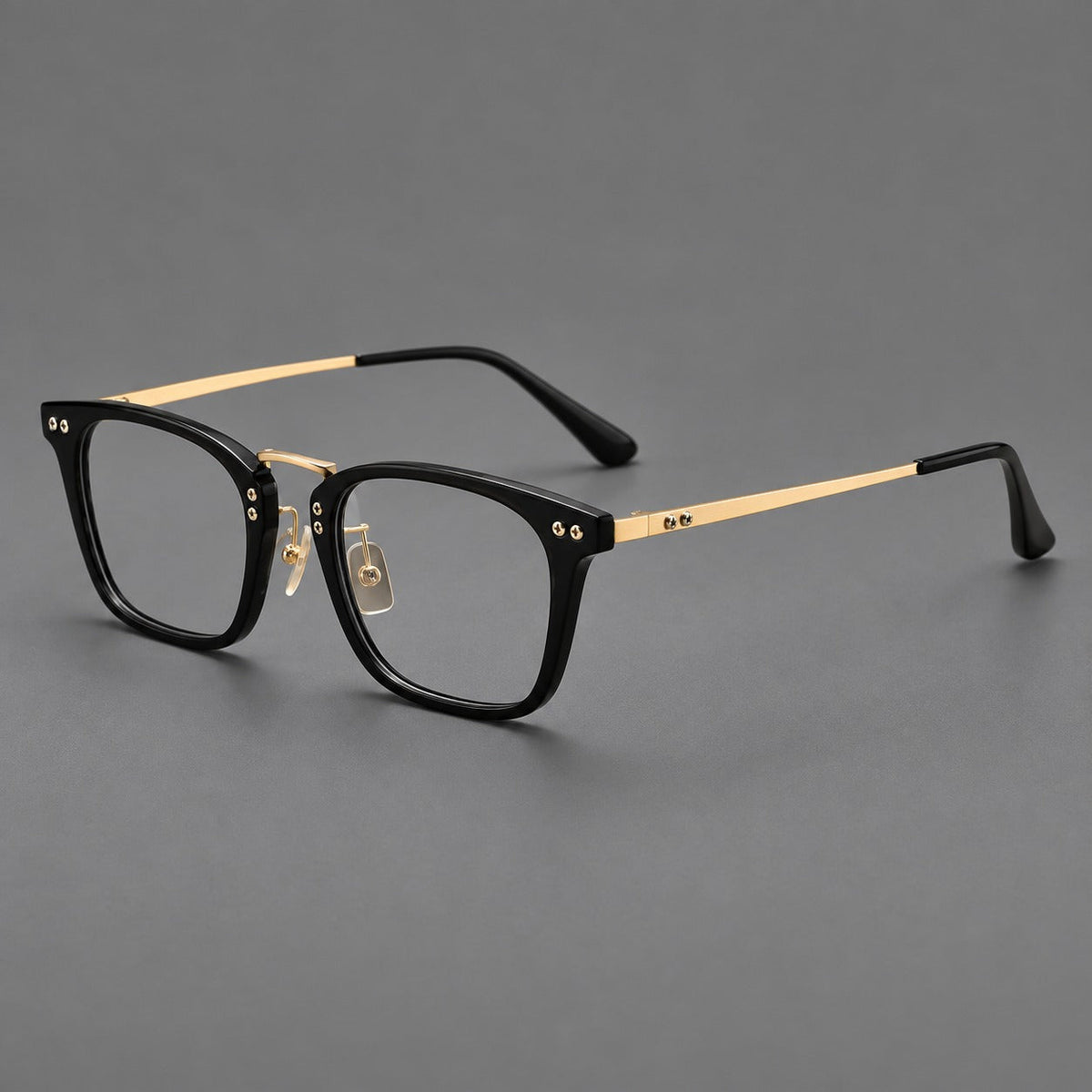 Acetate and titanium eyeglasses with angular rectangular rims and a curved metal bridge in Black / Gold, three quarter view