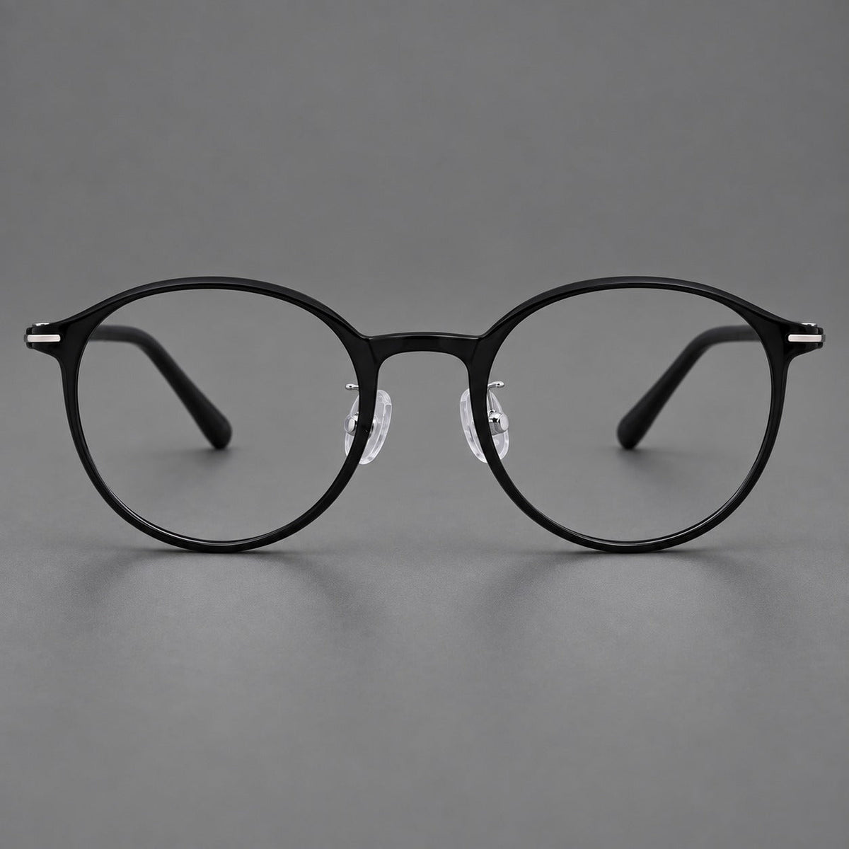 Compact round plastic eyeglasses with gently lifted corners and clear nose pads in Glossy Black, front view