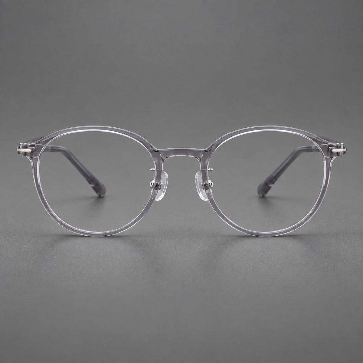 Compact round plastic eyeglasses with gently lifted corners and clear nose pads in Clear Gray, front view