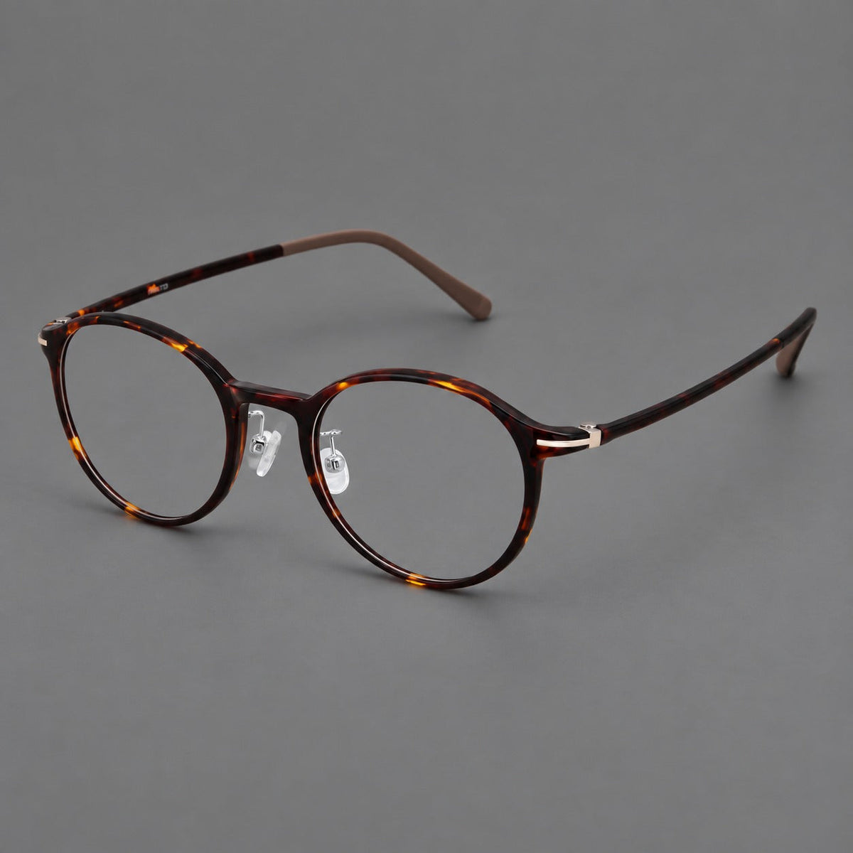 Compact round plastic eyeglasses with gently lifted corners and clear nose pads in Tortoiseshell, three quarter view