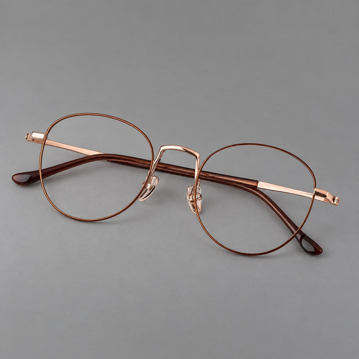 Retro round titanium glasses with a raised bridge and smooth corner shoulders in Brown and Rose Gold, three quarter view
