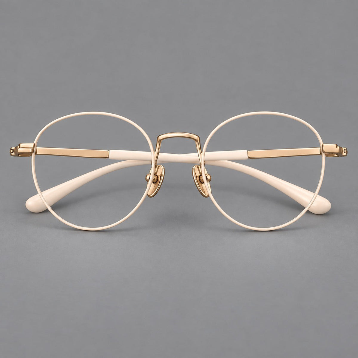 Retro round titanium glasses with a raised bridge and smooth corner shoulders in Cream and Gold, front view