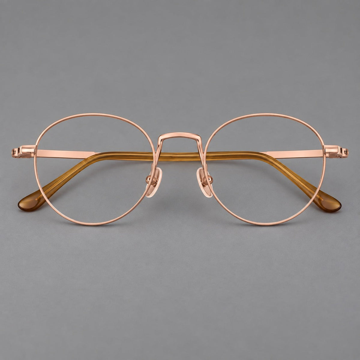 Retro round titanium glasses with a raised bridge and smooth corner shoulders in Rose Gold, front view