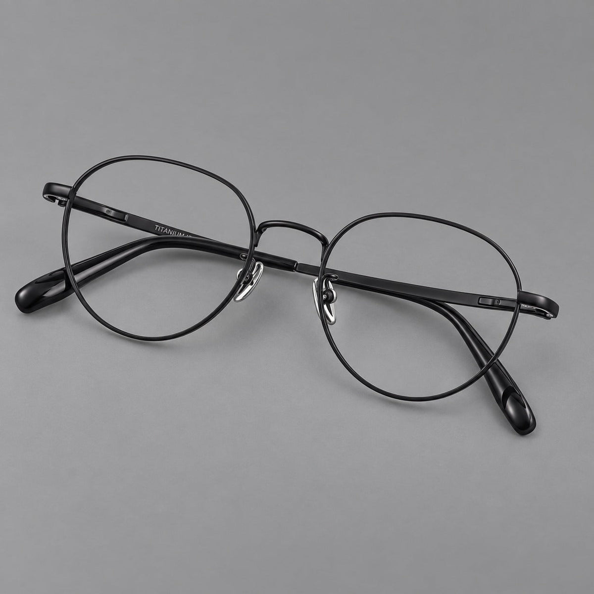 Classic round titanium glasses with broad flat temples and inset hinge details in Black, three quarter view