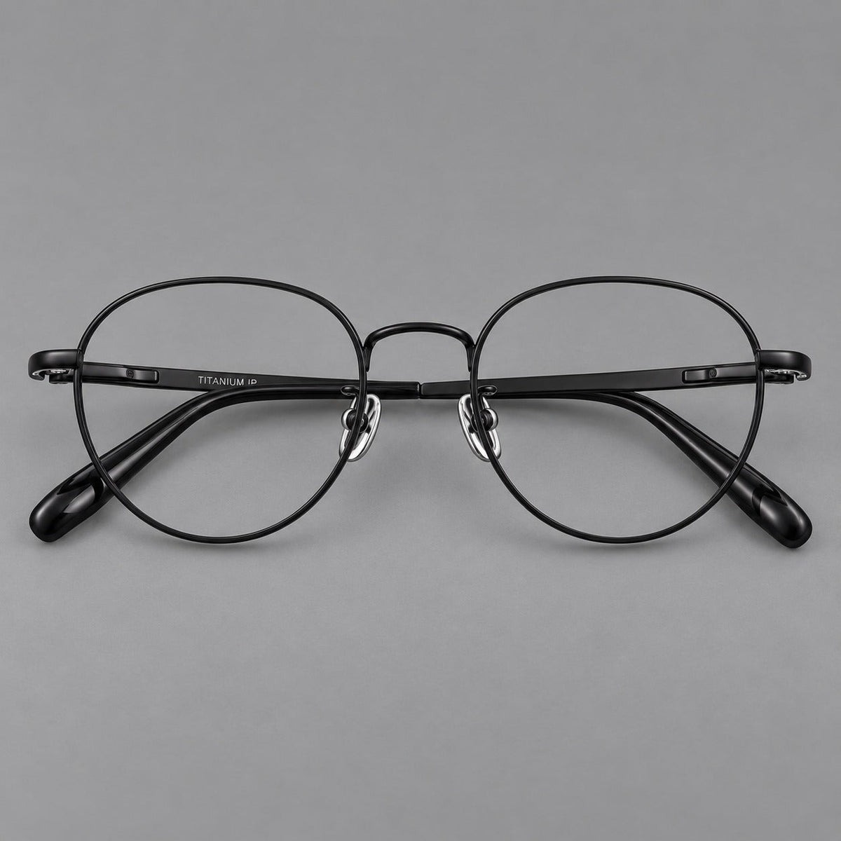 Classic round titanium glasses with broad flat temples and inset hinge details in Black, front view