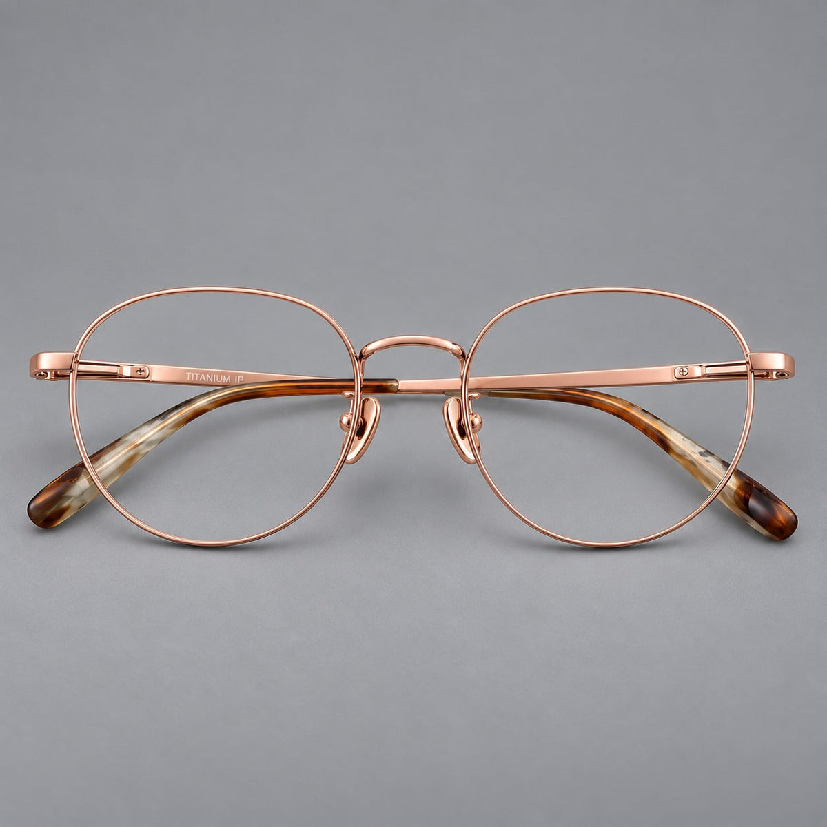 Classic round titanium glasses with broad flat temples and inset hinge details in Rose Gold, front view