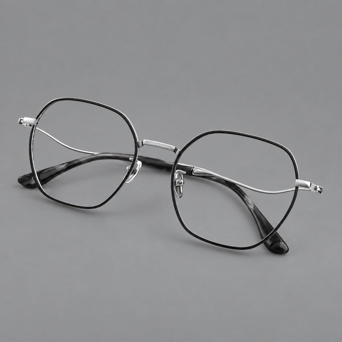 Geometric titanium glasses with engraved rim edges and curved temple joins in Black and Silver, three quarter view