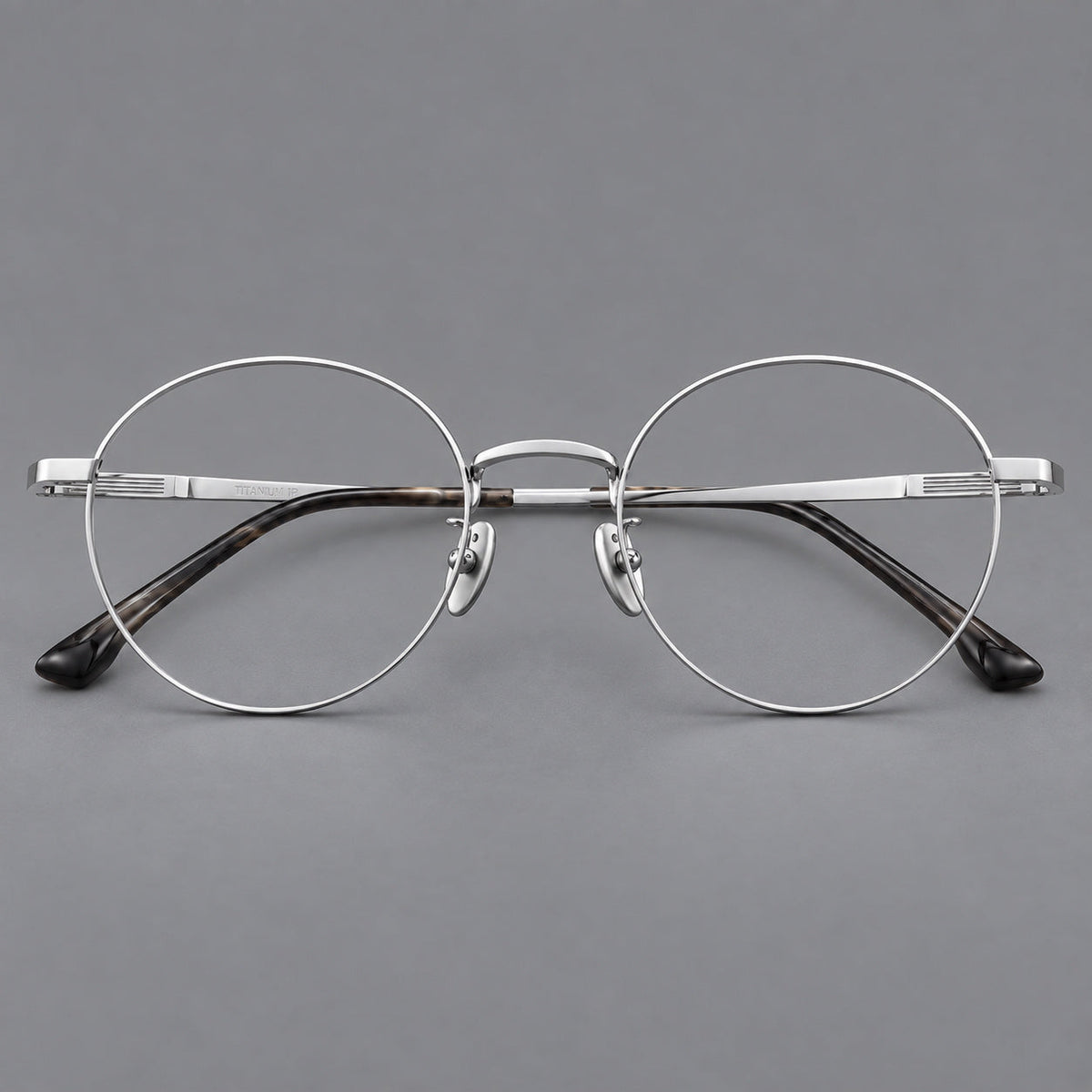 Classic circular titanium glasses with a raised bridge and lined temple accents in Silver, front view