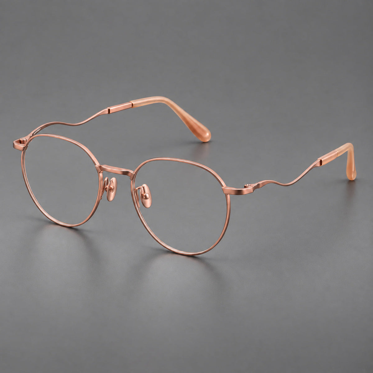 Rounded titanium glasses with a short bridge and distinctive wavy metal temples in Rose Gold, three quarter view