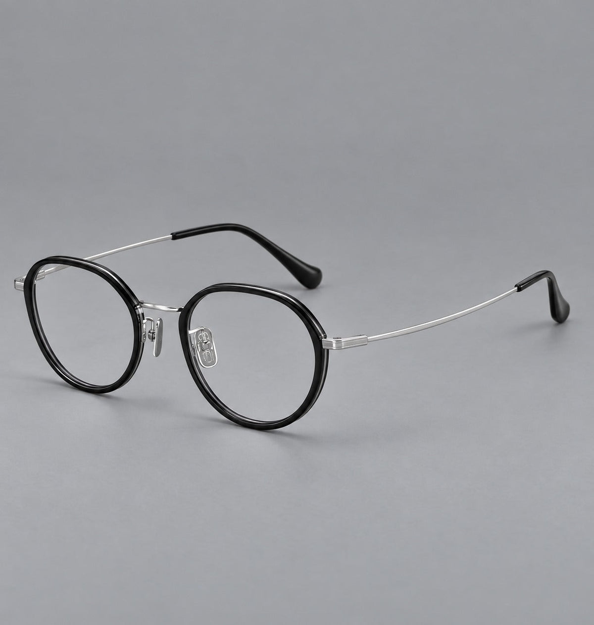 Rounded eyeglasses in acetate and titanium with gently arched brows and engraved metal temples in Black / Silver, three quarter view