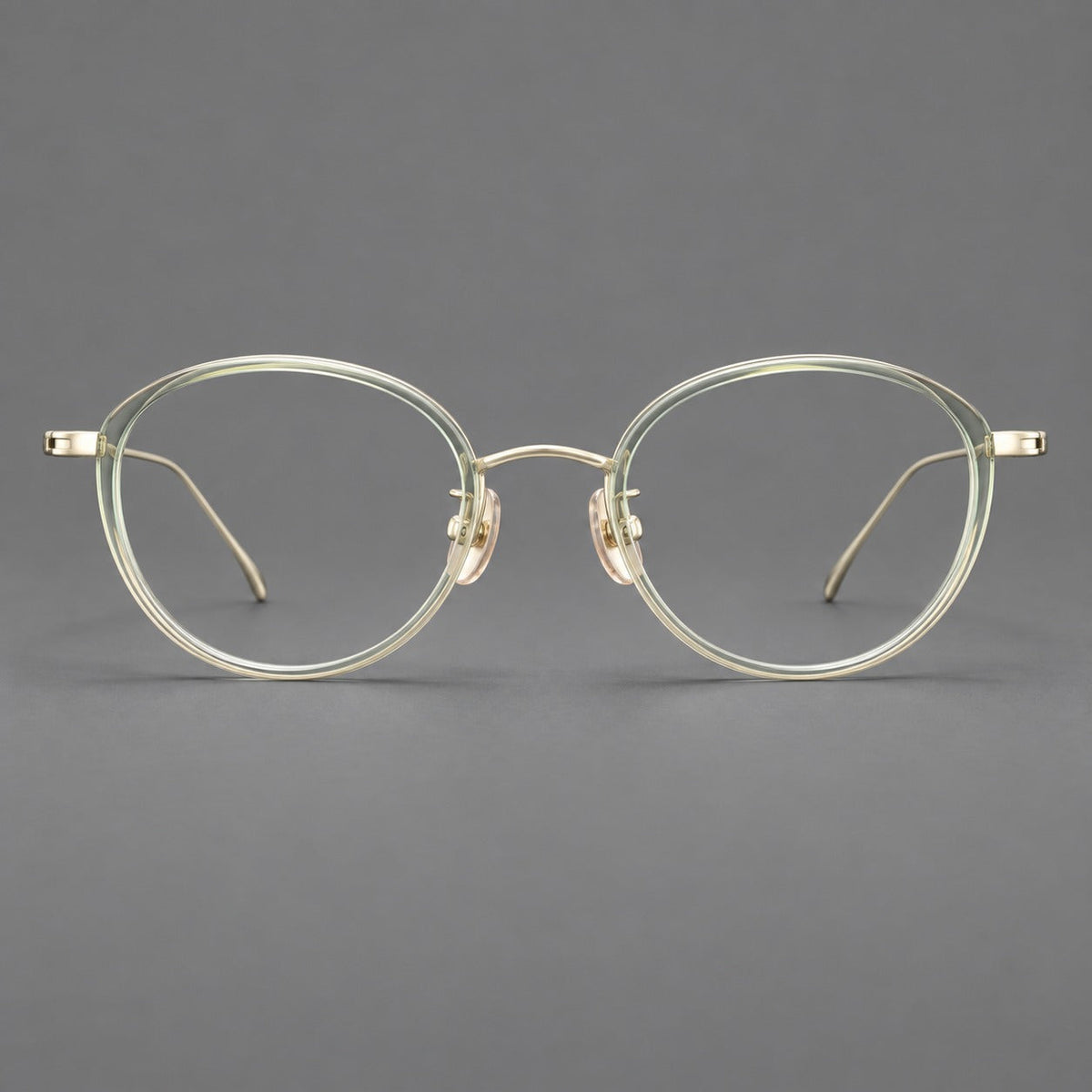 Round eyeglasses in acetate and titanium with a slim curved bridge and fine metal temples in Green / Gold, front view