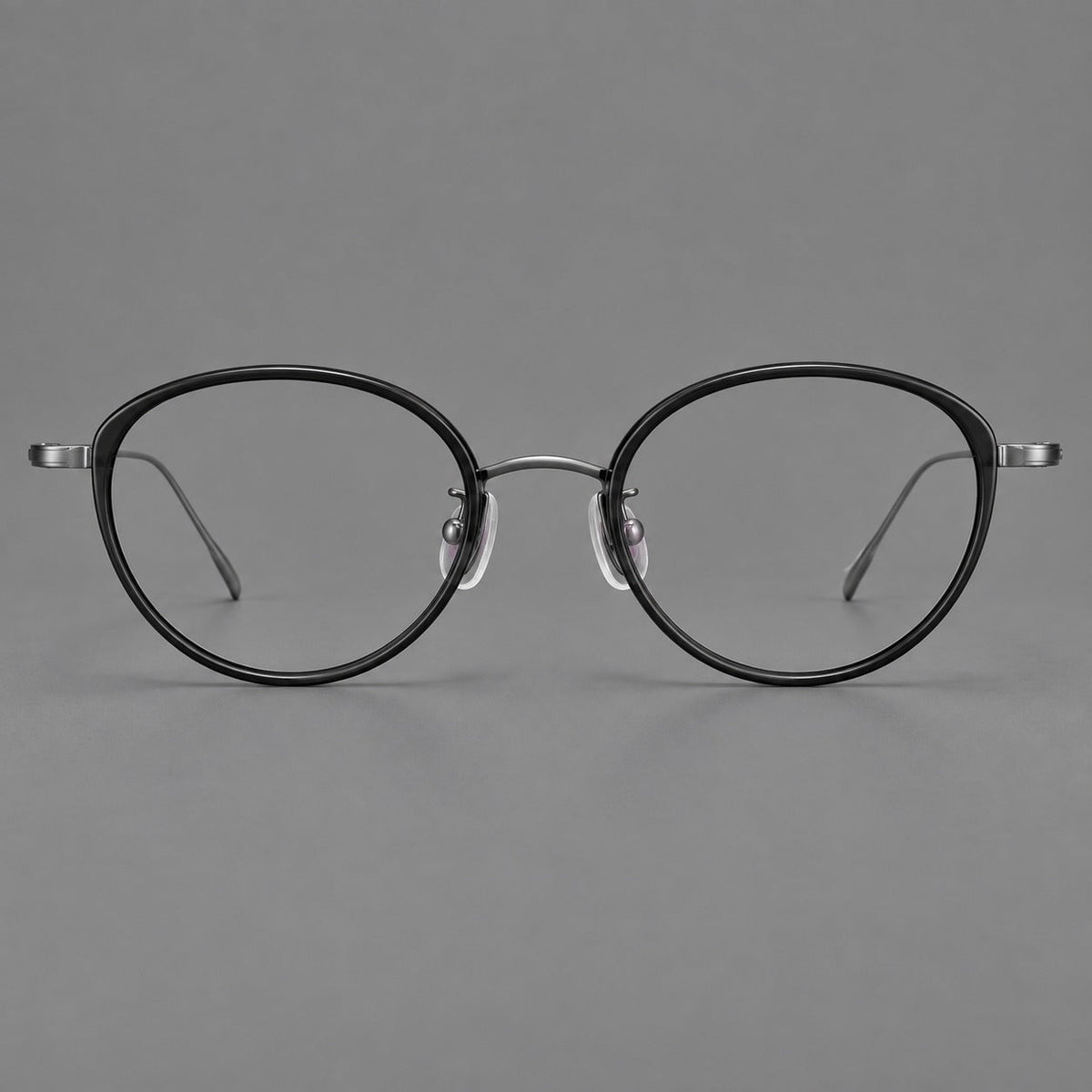 Round eyeglasses in acetate and titanium with a slim curved bridge and fine metal temples in Glossy Black / Gunmetal, front view