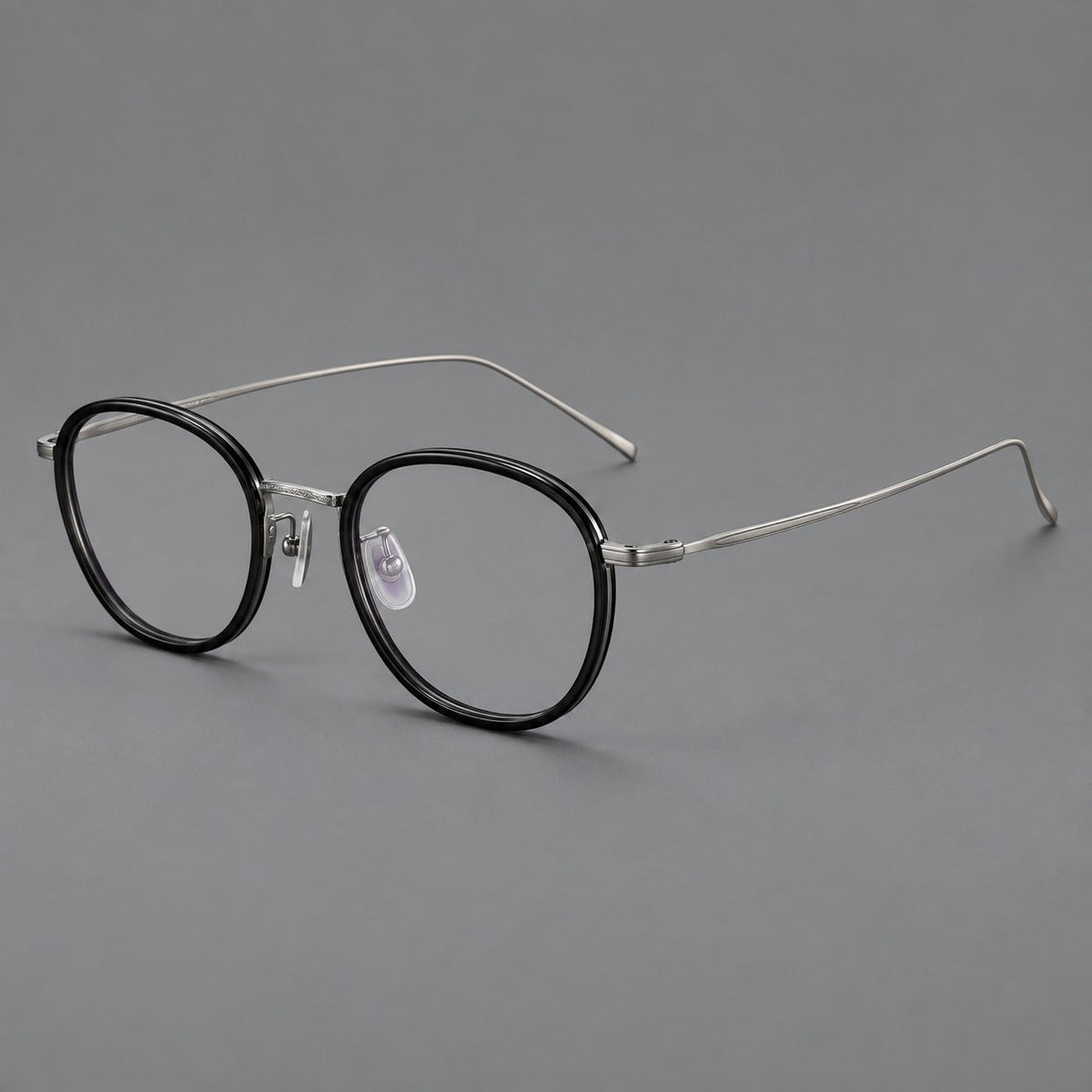 Vintage round eyeglasses in acetate and titanium with an engraved bridge and slender temples in Glossy Black / Gunmetal, three quarter view