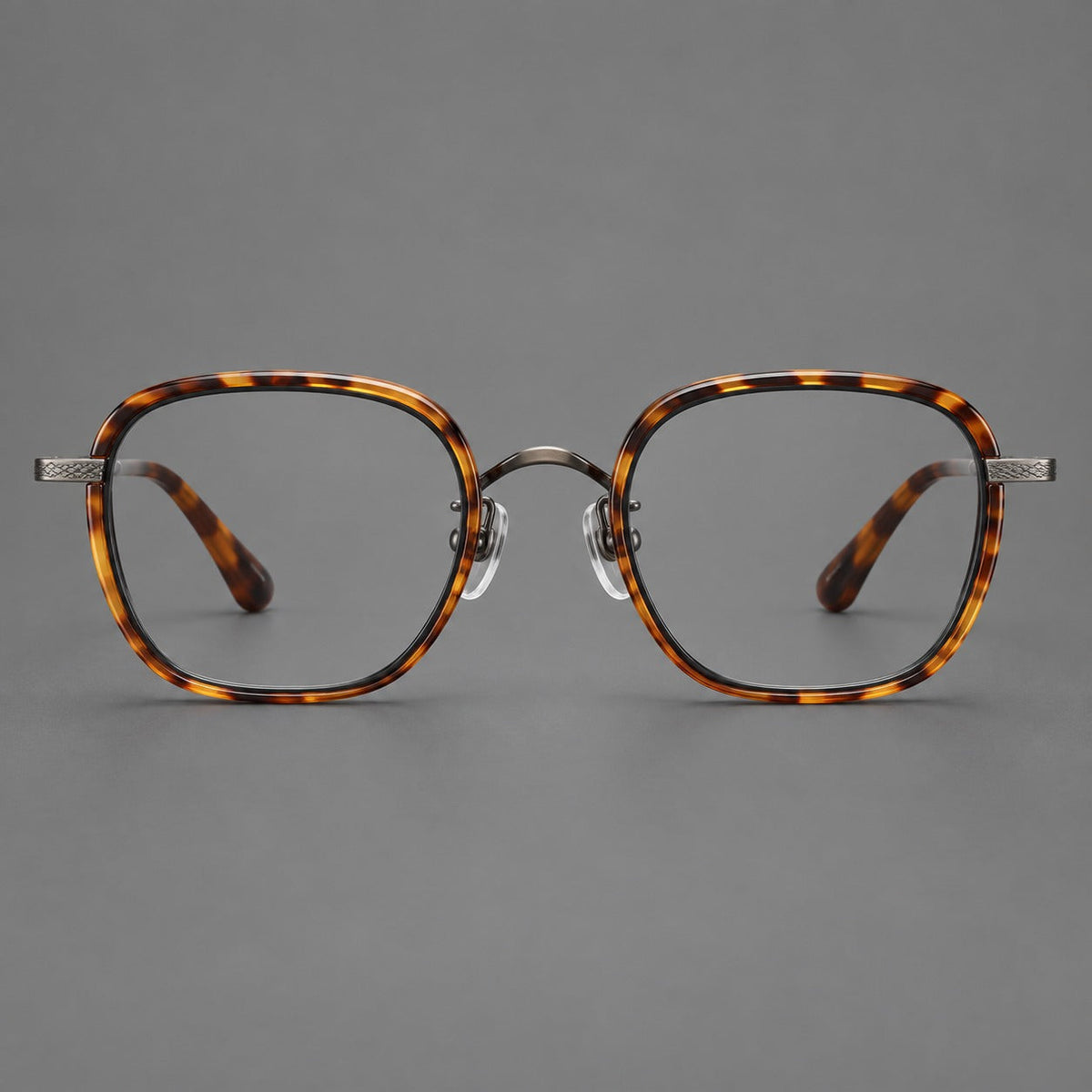 Rounded square eyeglasses in acetate and titanium with an arched bridge and engraved temples in Amber Tortoiseshell / Gunmetal, front view
