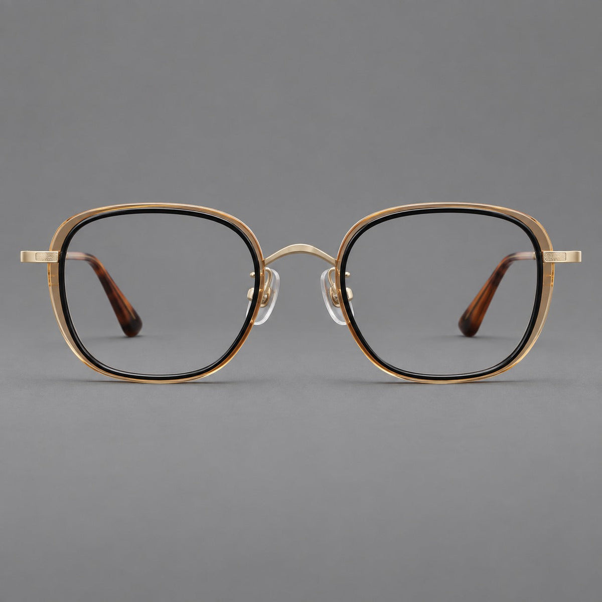 Rounded square eyeglasses in acetate and titanium with an arched bridge and engraved temples in Black and Clear Tea / Light Gold, front view