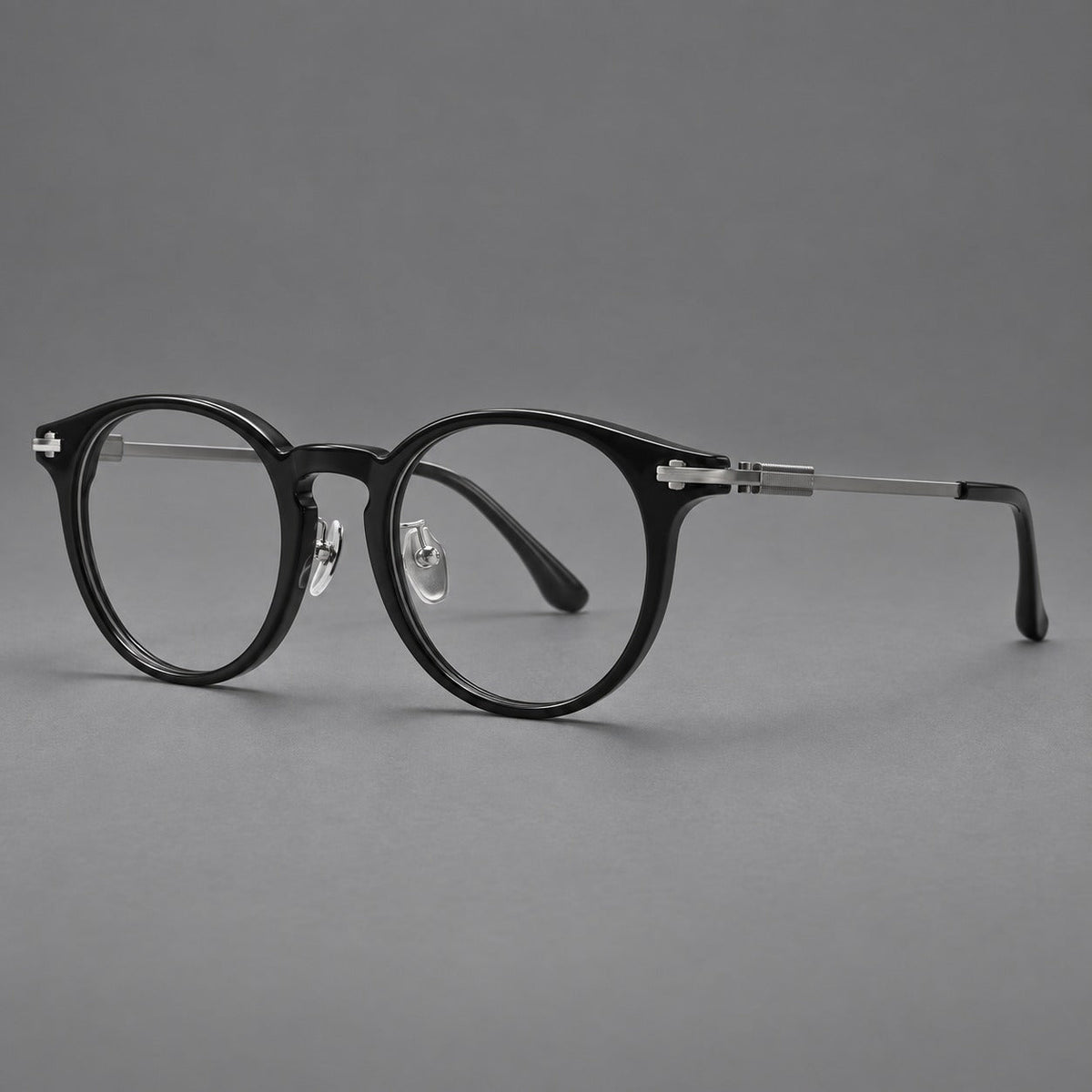Retro acetate and titanium eyeglasses with round rims and a pronounced keyhole bridge in Black / Gray, three quarter view