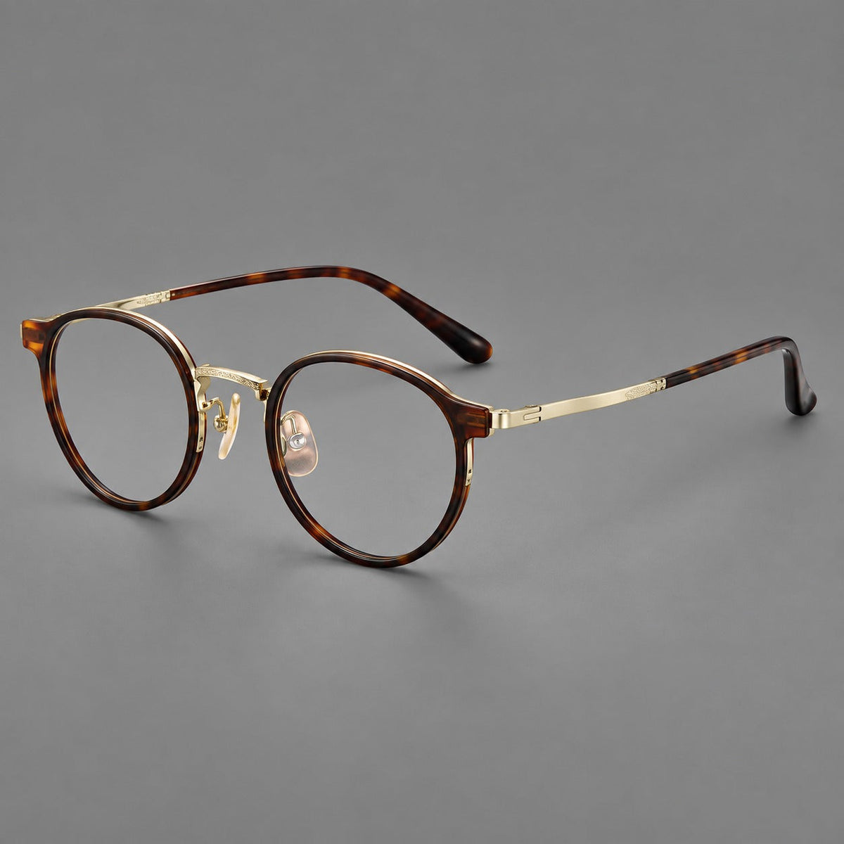 Round eyeglasses in acetate and titanium with widened outer corners and slender metal temples in Tortoiseshell / Gold, three quarter view