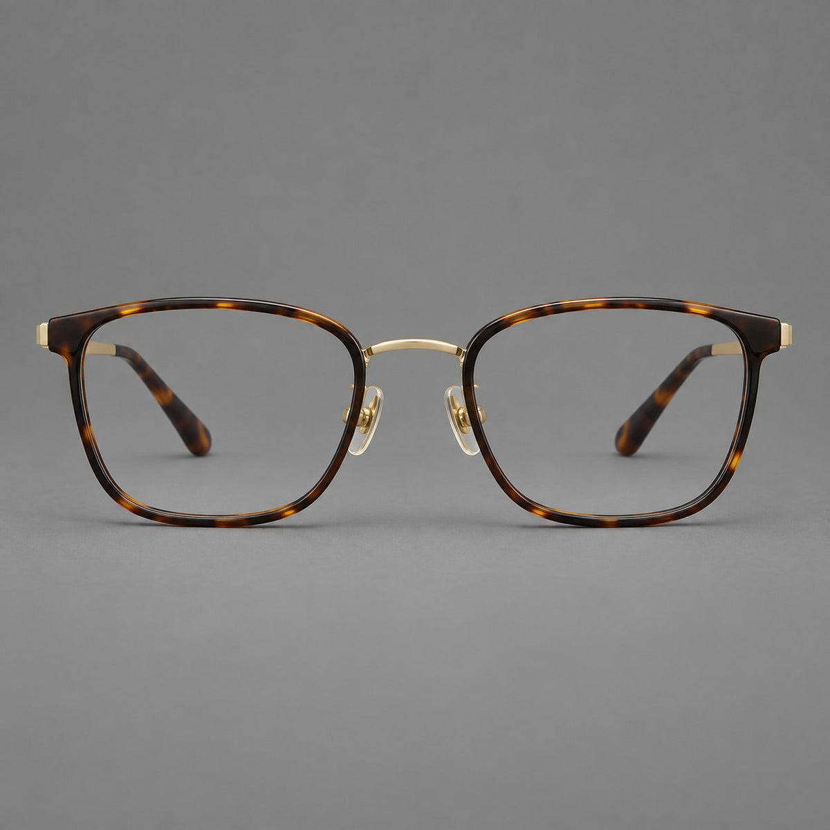 Rounded rectangular eyeglasses in acetate and titanium with bold corners and engraved metal temples in Tortoiseshell / Gold, front view