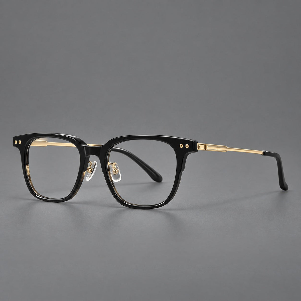 Classic acetate and titanium eyeglasses with squared brows and paired corner rivets in Black / Gold, three quarter view