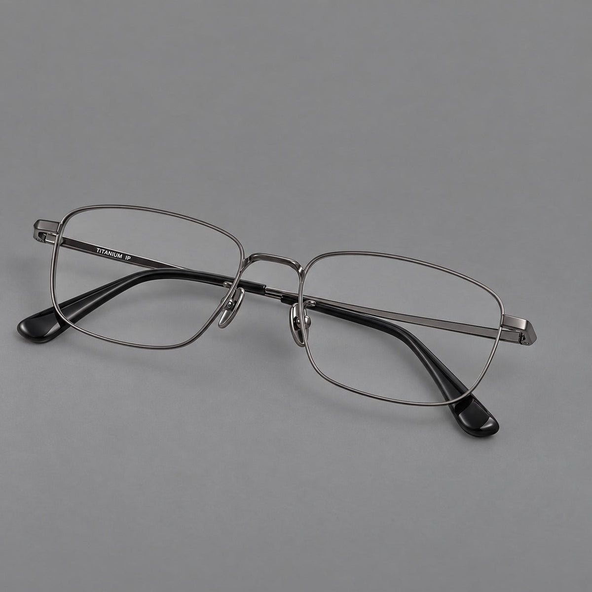 Modern square titanium glasses with an angular bridge and broad straight temples in Gunmetal, three quarter view