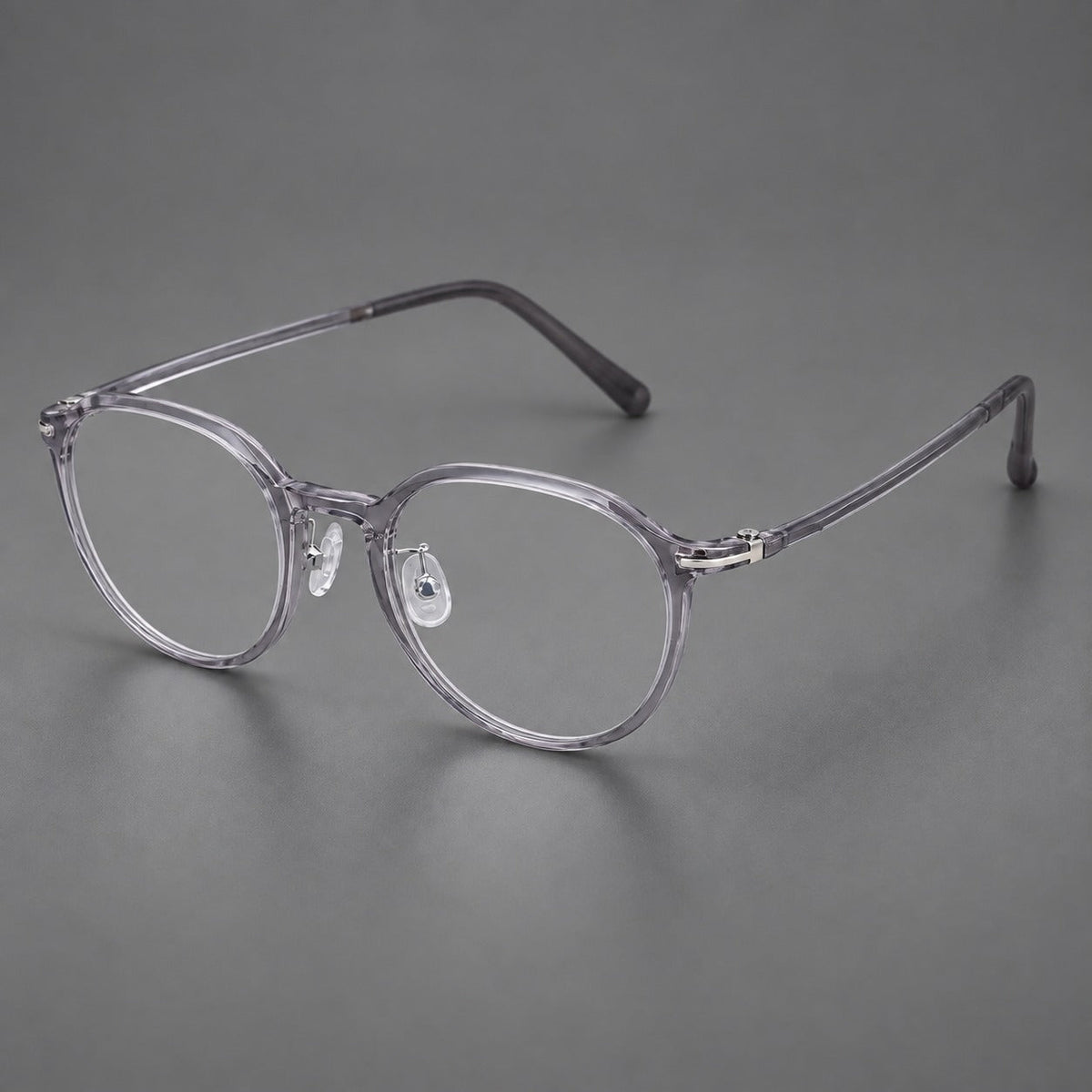 Compact round plastic eyeglasses with gently lifted corners and clear nose pads in Clear Gray, three quarter view