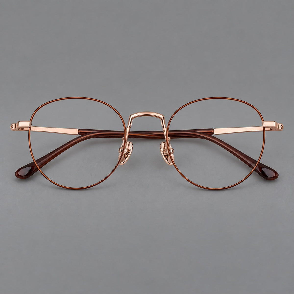 Retro round titanium glasses with a raised bridge and smooth corner shoulders in Brown and Rose Gold, front view