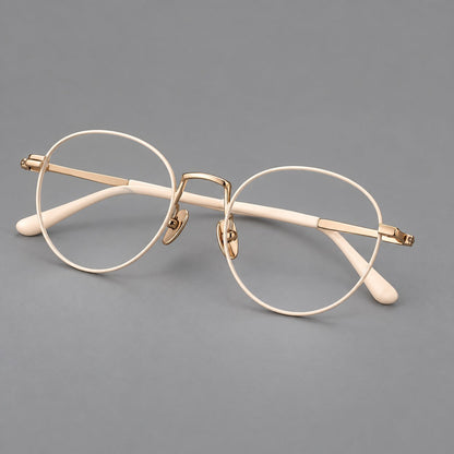 Retro round titanium glasses with a raised bridge and smooth corner shoulders in Cream and Gold, three quarter view lens detail