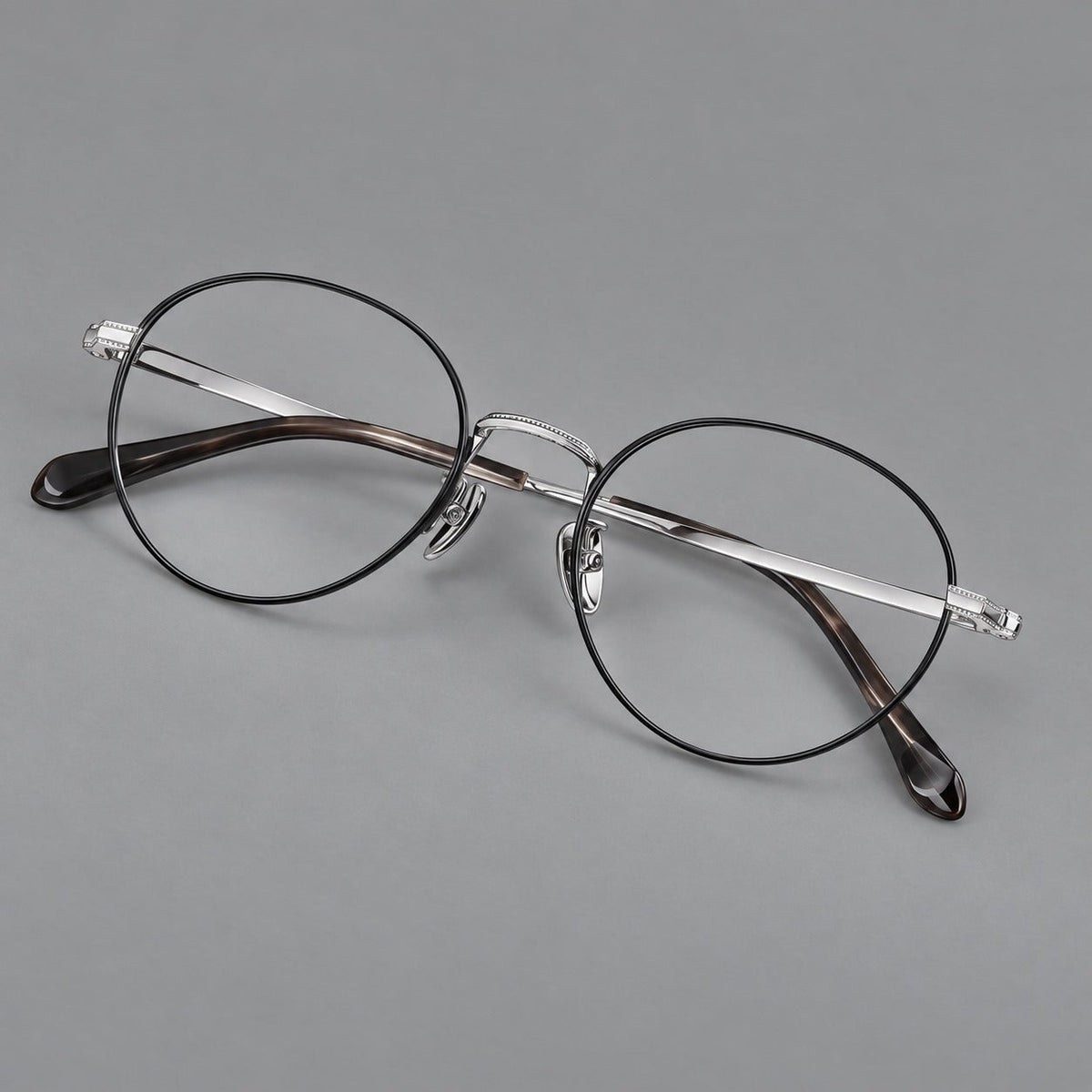 Rounded panto titanium glasses with a raised bridge and dotted temple accents in Black and Silver, three quarter view