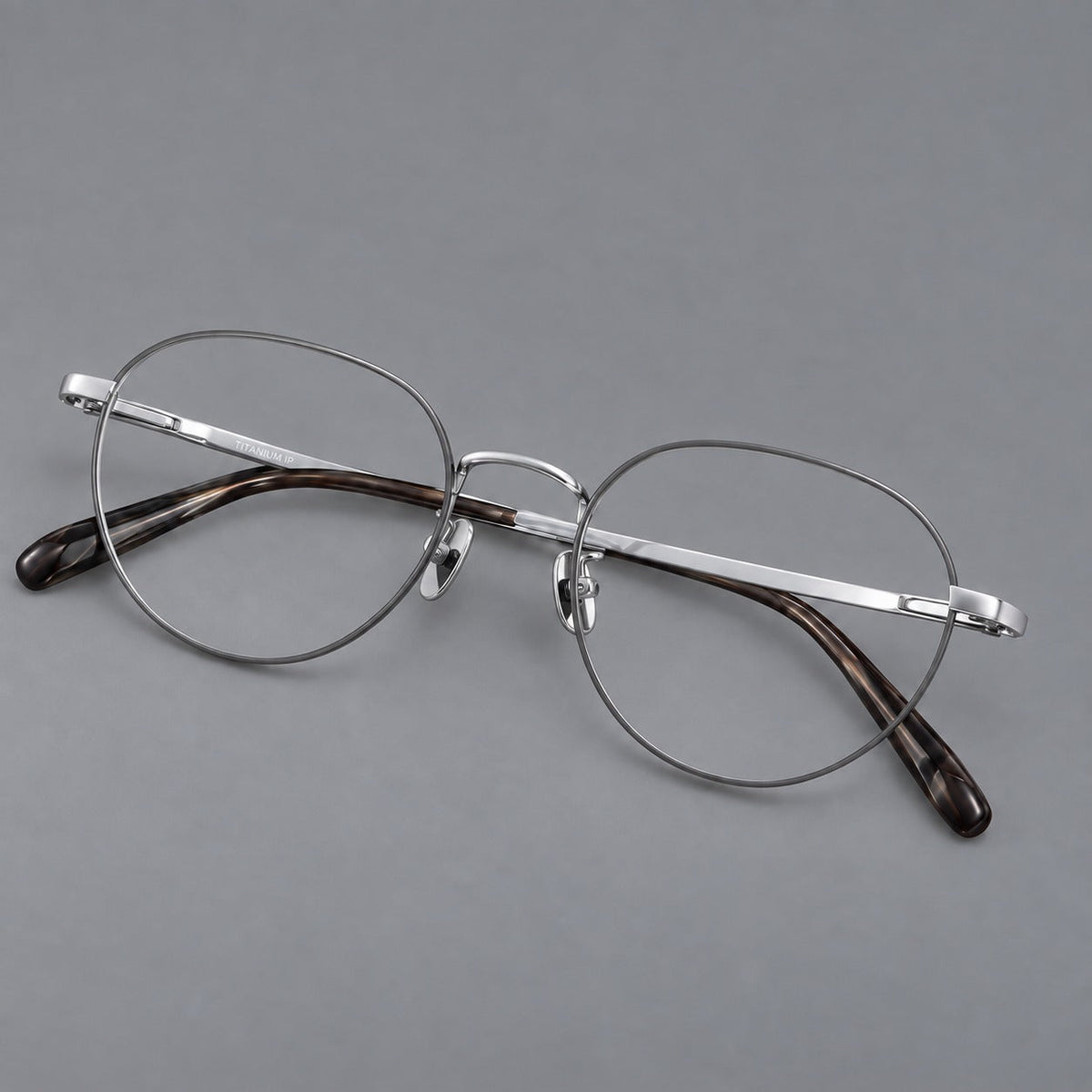 Classic round titanium glasses with broad flat temples and inset hinge details in Gray and Silver, three quarter view