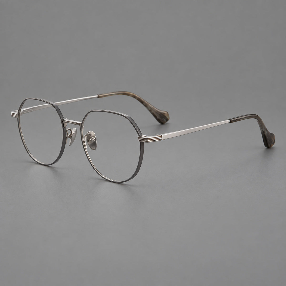 Geometric titanium glasses with soft polygonal rims and fine shoulder detailing in Gray and Silver, three quarter view