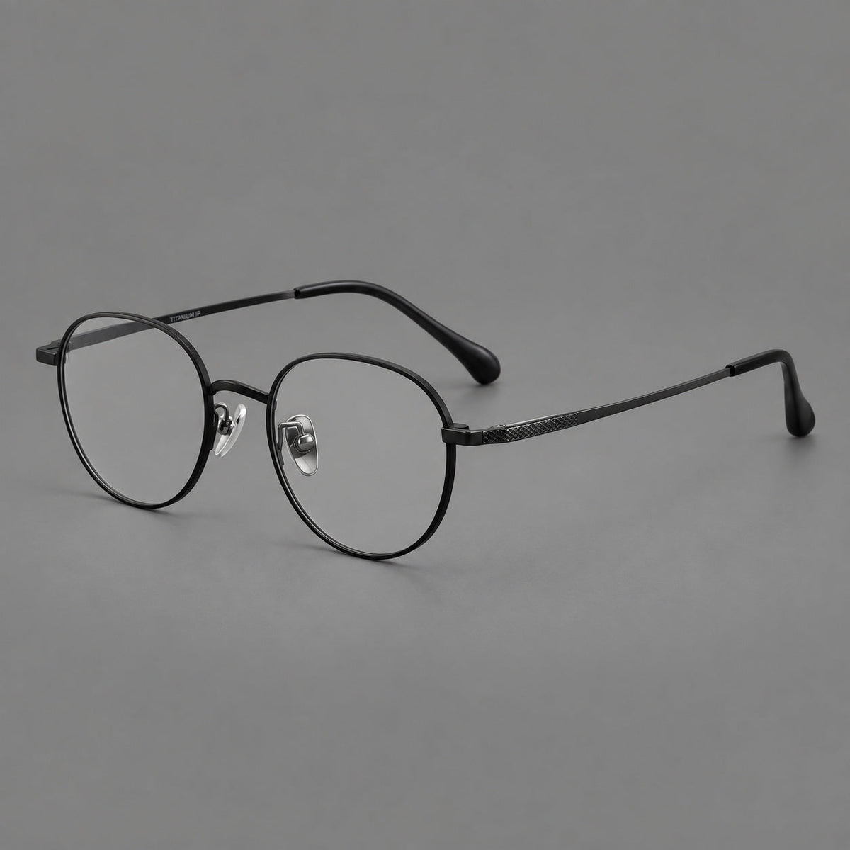 Compact round titanium glasses with an arched bridge and textured temple accents in Black, three quarter view
