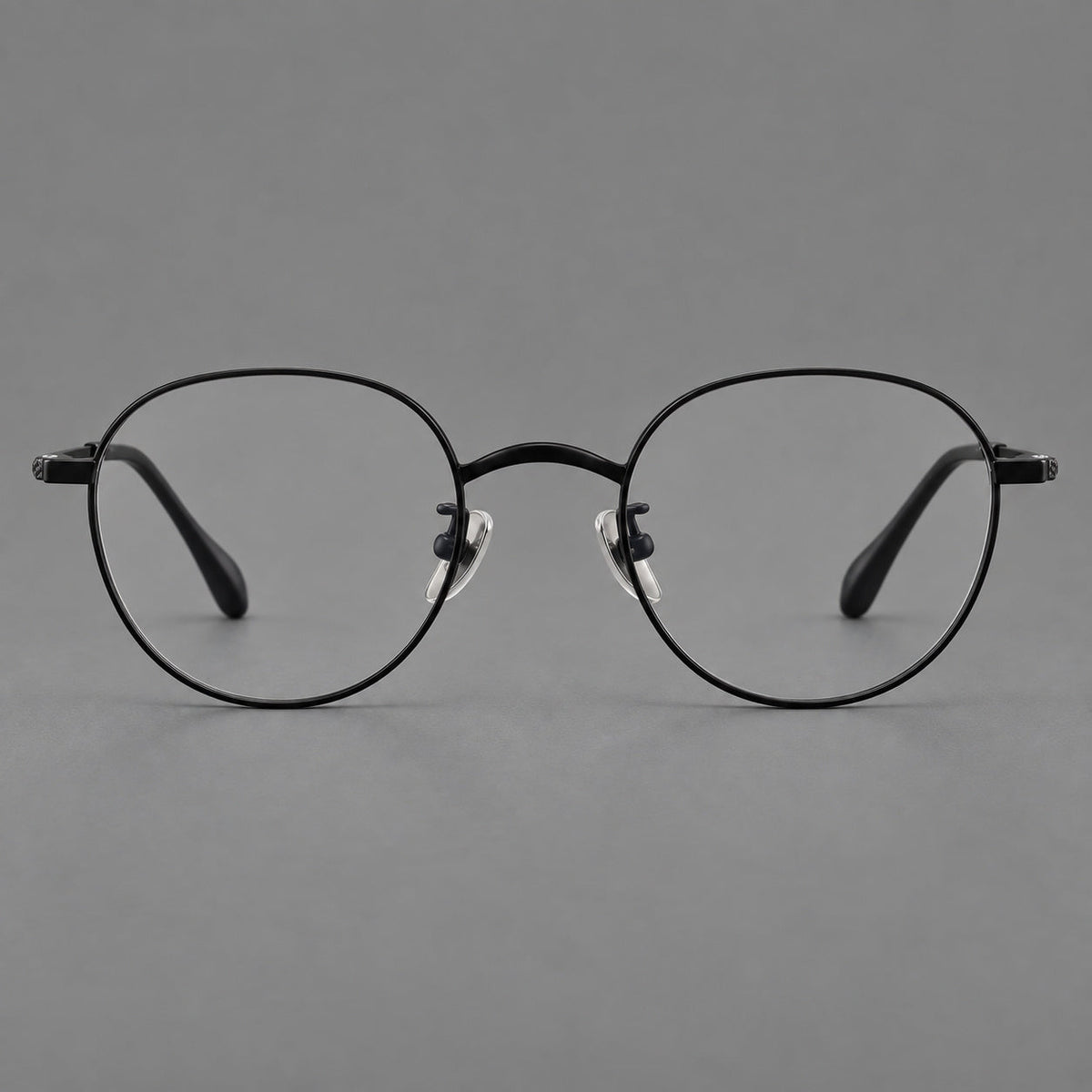 Compact round titanium glasses with an arched bridge and textured temple accents in Black, front view