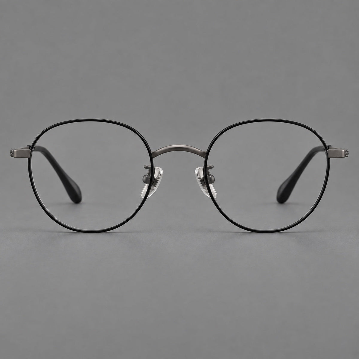 Compact round titanium glasses with an arched bridge and textured temple accents in Black and Gunmetal, front view