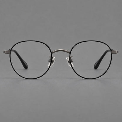 Compact round titanium glasses with an arched bridge and textured temple accents in Black and Gunmetal, front view frame detail