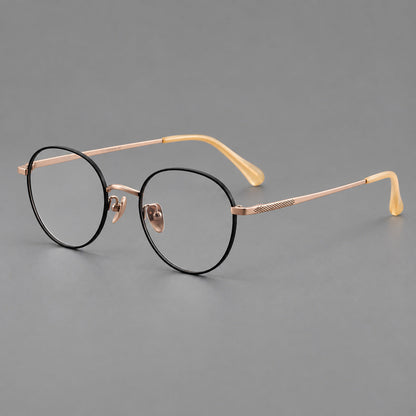Compact round titanium glasses with an arched bridge and textured temple accents in Black and Rose Gold, three quarter view lens detail