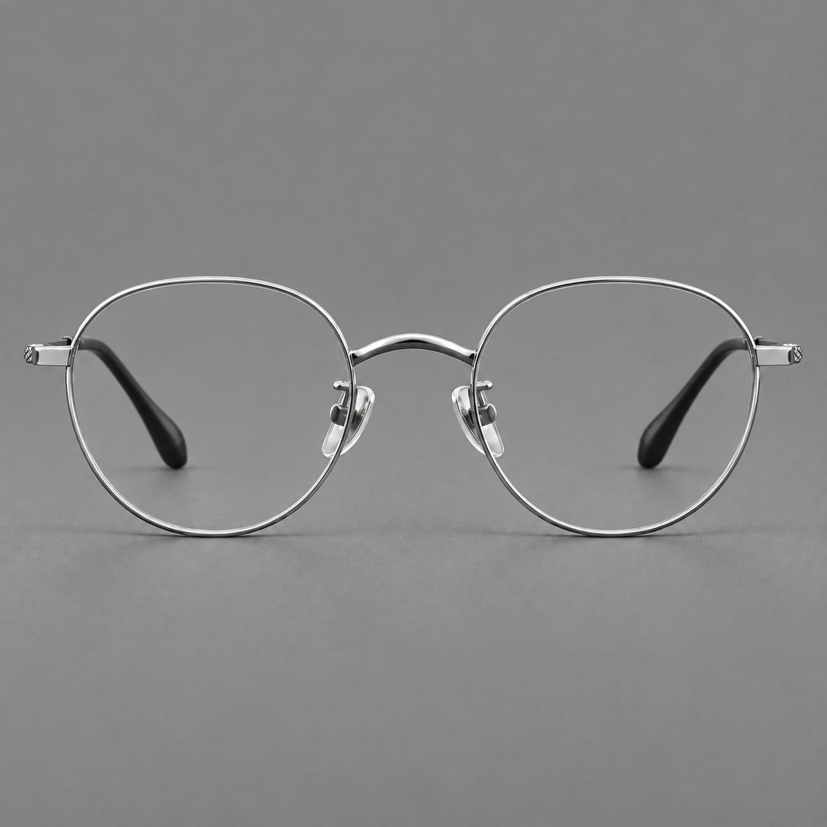 Compact round titanium glasses with an arched bridge and textured temple accents in Silver, front view
