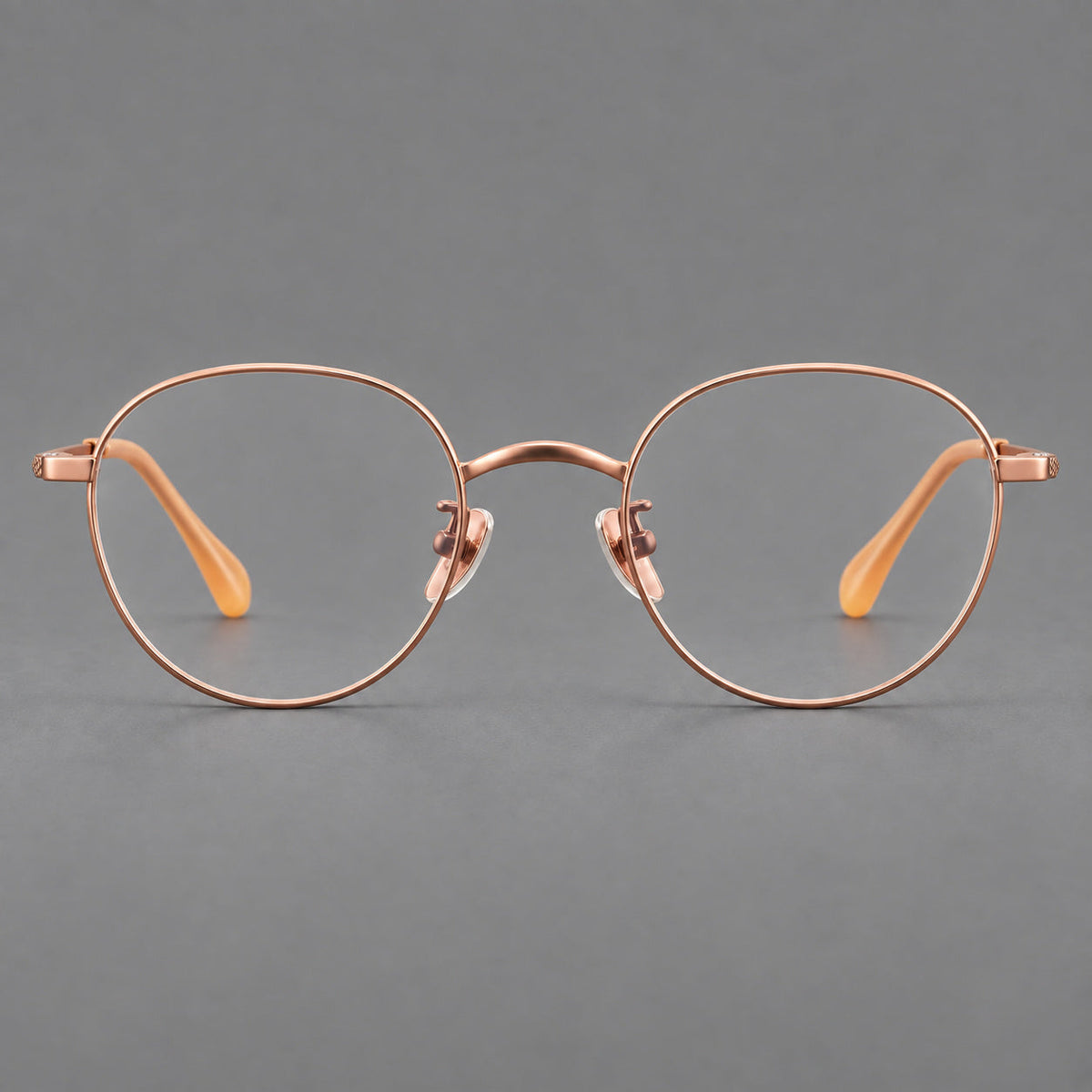 Compact round titanium glasses with an arched bridge and textured temple accents in Rose Gold, front view