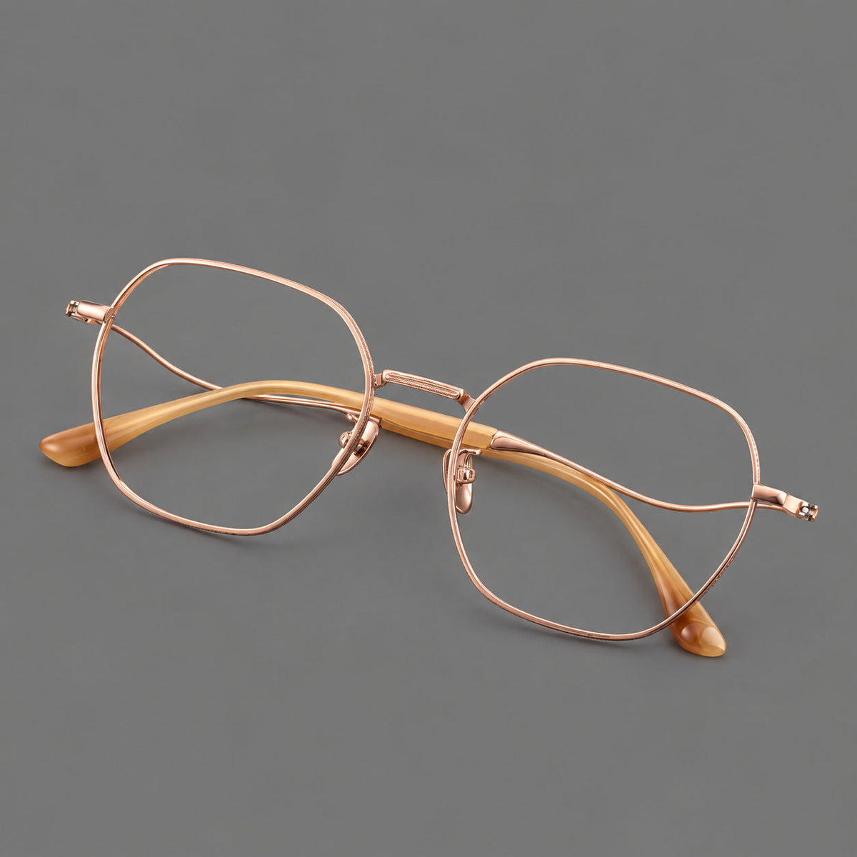 Geometric titanium glasses with engraved rim edges and curved temple joins in Rose Gold, three quarter view